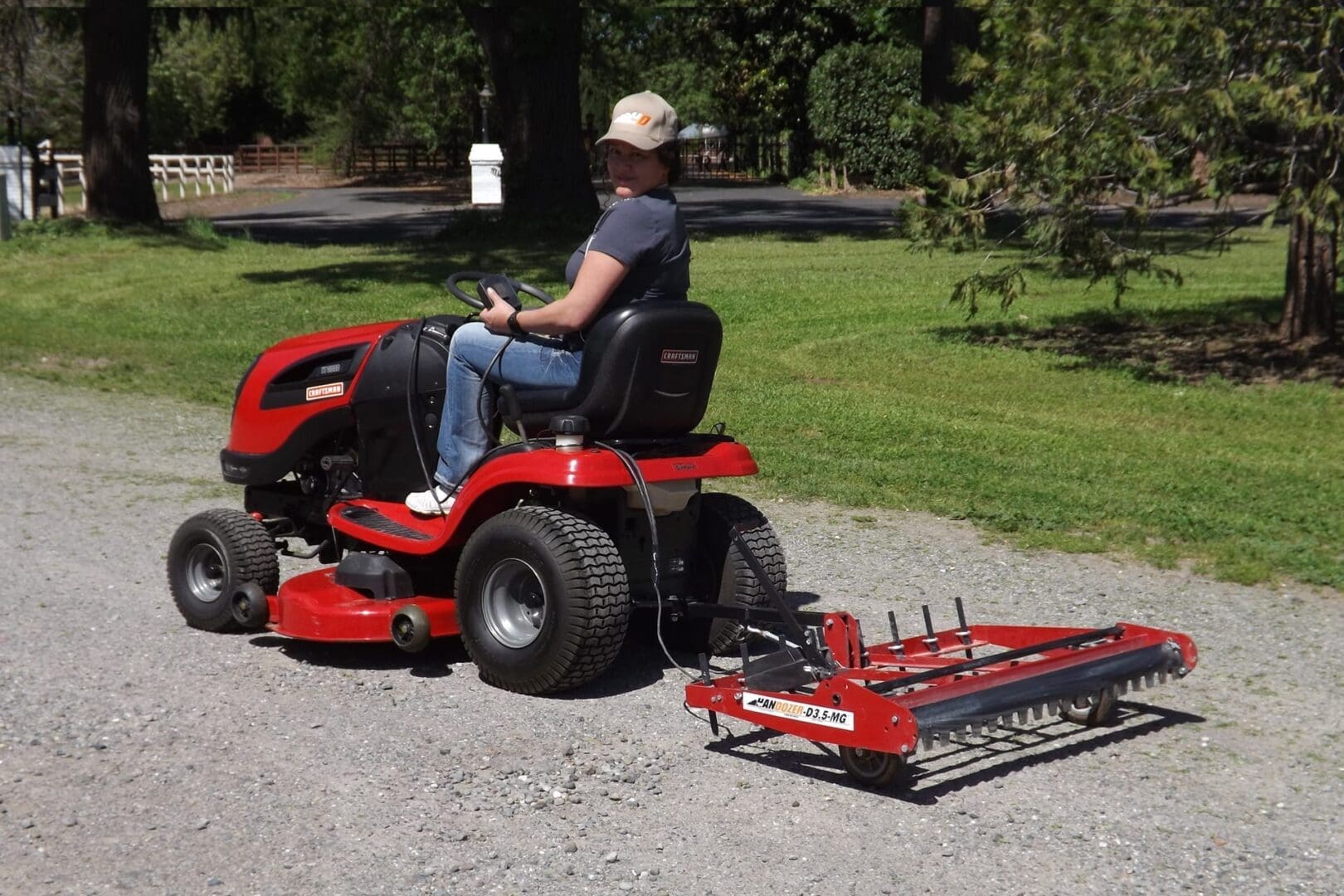 A woman riding a lawn mower with a leveling drag